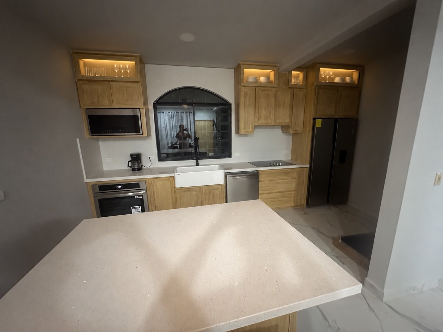 Remodeled kitchen with illuminated upper display cabinets and large island