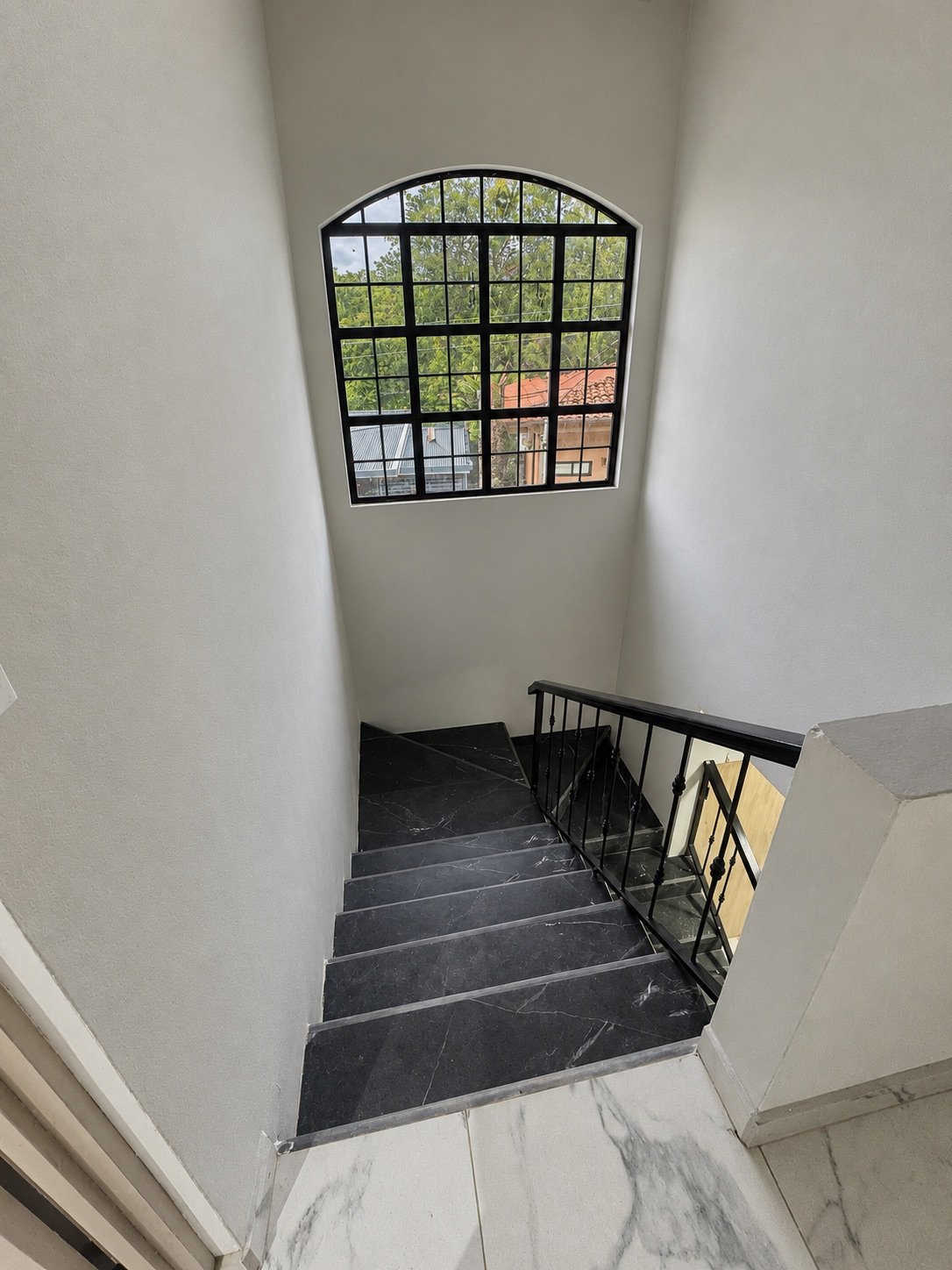 Remodeled staircase with stone-look treads and black metal railing